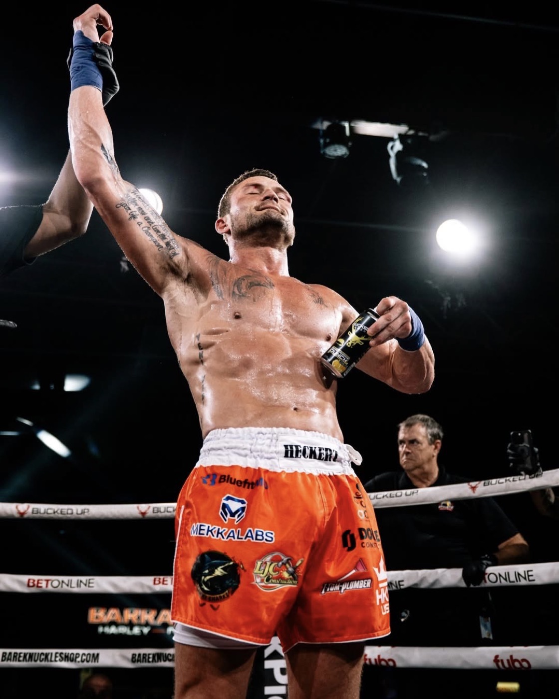 Mike Heckert has his hand raised after victory at BKFC Clearwater with sponsor logos visible